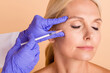 © deagreez - Close up photo middle aged woman undergo plastic surgery doctor make injection with syringe isolated beige color background