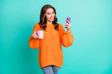 Sticker - Photo of young beautiful attractive happy smiling girl drink tea using smartphone isolated on turquoise color background