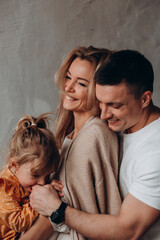 Wall Mural - Photoshoot of a happy young family. Dad, mom and daughter. Studio photography.