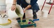 © VAKSMANV - Close up of Caucasian young handsome man pouring green olive paint preparing for painting walls in house renovating and redesigning room. Handyman working on apartment redecoration repair and makeover