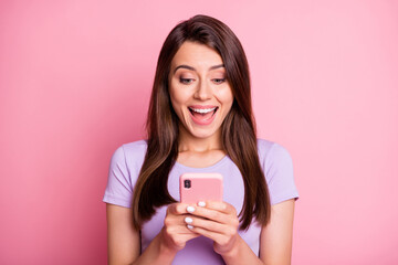 Sticker - Photo portrait of excited woman holding phone in two hands with open mouth isolated on pastel pink colored background