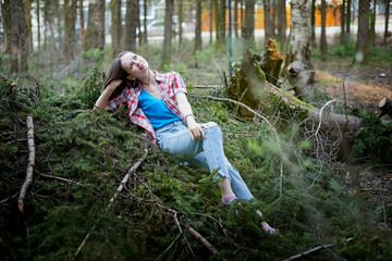 Beautiful young brunette woman with long hair in a forest pines and firs on a summer day