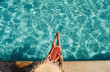 © standret - Young woman sits near swimming pool at daytime with watermelon