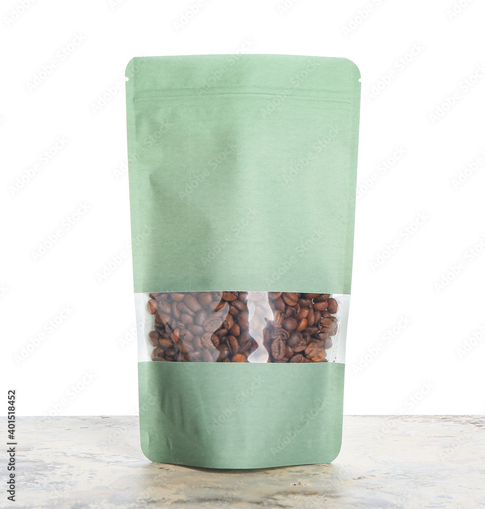 Bag with coffee beans on table against white background