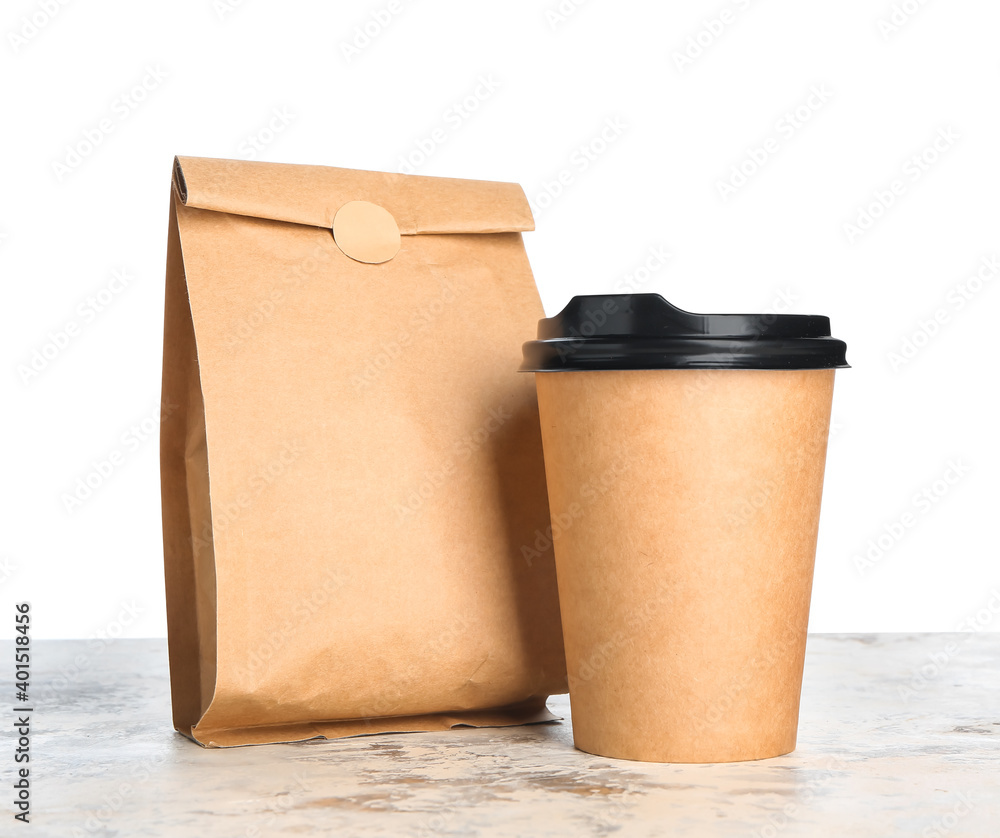 Bag with coffee and cup on table against white background