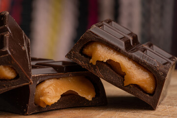 Pieces of chocolate bar filled with chocolate and vanilla cream on wooden plate