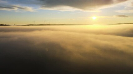 Poster - Wind turbines produce environmentally friendly energy. Stunning aerial shots of drone above the clouds during sunrise with wind turbines in the back