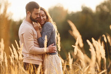 Beautiful agricultural field. Cheerful lovely young couple having a rest outdoors together