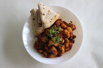 Wall Mural - Spiced potatoes and cauliflower served with flat indian bread