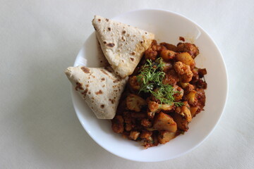 Wall Mural - Spiced potatoes and cauliflower served with flat indian bread