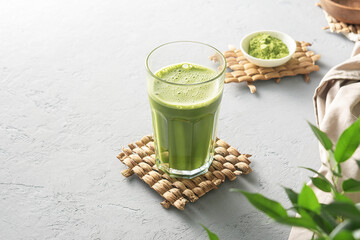 A tall glass of matcha tea on a gray concrete background.