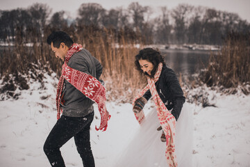 wedding couple running lying in snow laughing having fun playing snowballs