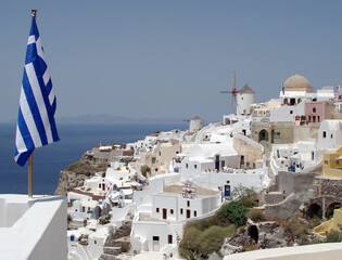 View of windmills with Greece flag in Oia village on island of Santorini, Greece, Europe