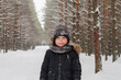 © Olga - European boy in the forest in a hat in winter on the background of snow.