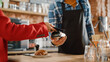 © Gorodenkoff - Close Up of a Feminine Hand Holding a Smartphone with an NFC Payment Technology Used for Paying for Croissant in a Cafe. Customer Uses Mobile to Pay for Latte Through a Credit Card Terminal.
