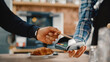 © Gorodenkoff - Close Up of a Masculine Hand Holding a Credit Card with an NFC Payment Technology Used for Paying for Take Away Coffee in a Cafe. Customer Uses Debit Card to Pay for Cappuccino Through Bank Terminal.