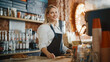 Beautiful Young Caucasian Barista with Blond Hair is Making a Cup of Fresh Coffee in a Cafe. Happy and Smiling Bar Employee Posing while Working in a Cozy Loft-Style Coffee Shop Restaurant Counter.