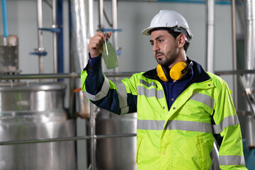 engineer or factory worker holding green basil seeds drink for checking quality in beverage factory