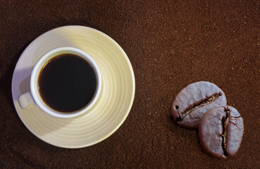 Black hot coffee in a white cup with a saucer and ground coffee on the table close-up.