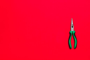 Wall Mural - Quality green building pliers tool to compress something or repair a car or house on red background. Do it yourself instrument. Banner for advertising construction shop with copy space. Business card