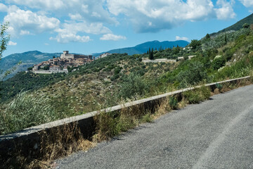 Mountain road view with medieval city on the background on a beautiful summer or spring sunny day with blue sky