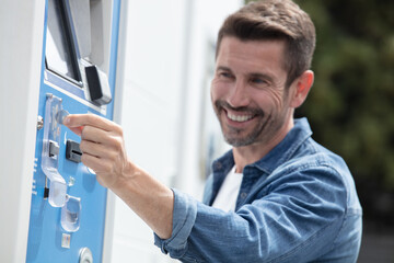 middle aged man paying at parking meter