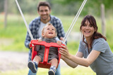 happy young family couple having fun on a swing