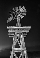 A Vertical Shot Of A Wooden House Windmill At Night