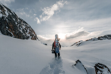 Wall Mural - A beautiful shot of a snowboarder walking into the snow on the mountains