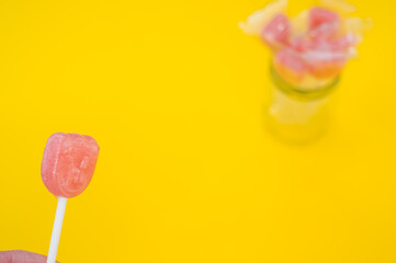 Sticker - A selective focus shot of yummy candy and a lot of candies in a jar isolated on a yellow background