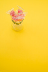 Sticker - A vertical shot of yummy candies in plastic bags in a jar isolated on a yellow background