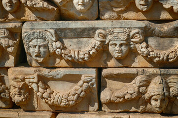 Poster - A horizontal shot of stone sculptures on an ancient building with people's face