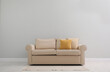 © New Africa - Comfortable beige sofa near light wall indoors, space for text. Simple interior