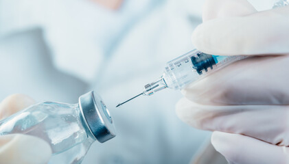 Doctor holding a syringe with a single bottle vial of Covid-19 vaccine for children or adults. Concept fight against virus. Close up detail. Medical concept vaccination hypodermic injection treatment.