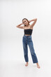 © Artem Zatsepilin - young attractive asian woman with long hair in black top, blue jeans isolated on white studio background. skinny pretty female posing on cyclorama with bare feet. model tests of beautiful lady