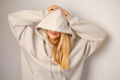© Iuliia Pilipeichenko - Young beautiful girl in a white hoodie posing. Warm oversized hoodie with an hood. Stylish trendy hipster bow. Trying on clothes in a store. Youth subculture. Fashion clothing advertising
