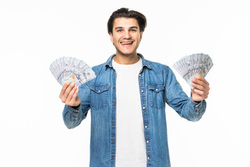 Portrait of a cheerful successful man in white shirt showing bunch of money banknotes in two hands while standing and celebrating isolated over white background