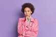 © wayhome.studio  - Horizontal shot of serious African American woman holds chin looks directly at camera dressed in stylish jacket poses against purple background has full lips curly bushy hair. Self confident girl