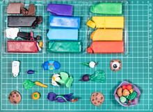 Top View Of Various Hand-crafted Figurines And Colorful Polymer Clay On Green Cutting Mat