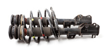 Two Shock Absorber Struts With Black Springs After Being Used On A Car During Replacement And Repair On A White Isolated Background. Used Spare Parts. Auto Parts Catalog.