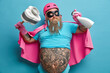 © wayhome.studio  - Enthusiastic bearded man pretends being cleaning superhero holds plunger with toilet paper and bottle of detergent has big tattooed belly thick beard wears pink cape isolated over blue background.