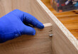 hand of craftsman in protective glove during wood furniture assembly from medium-density fibreboard