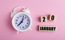 On A Pink Background, A White Alarm Clock And Wooden Cubes With The Date Of JANUARY 20