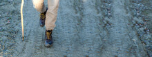 Horizontal Banner Copy Space Close-up Dirty Boots Of Hiker Man Walking In A Muddy Path. Unrecognizable Person In Outdoors Activities.