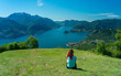 woman sitting on a mountain top admiring the view of lake and mountains