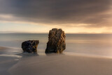 Fototapeta  - sunset on the beach with two rocks and long exposure