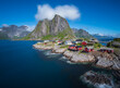 A small norway village with red houses and big mountain in the background with blue sky and white clouds 