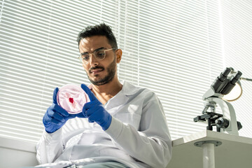 Sticker - Gloved young researcher in whitecoat looking at sample of raw vegetable meat