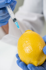 Sticker - Gloved hands of laboratory worker or scientist in whitecoat injecting ripe lemon