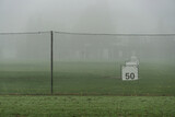 Fototapeta Na sufit - Golf driving range in autumn morning fog (behind fence)
